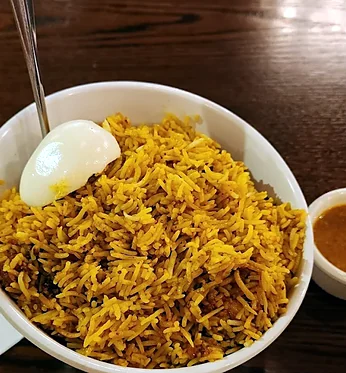Hyderabadi chicken dum biryani with a boiled egg and a cup of salan at Bawarchi in Mississauga
