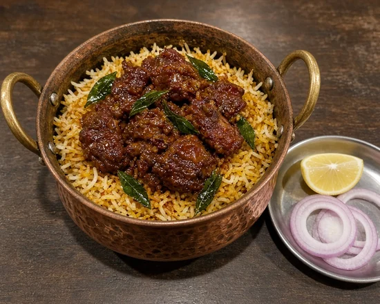 Mutton ghee roast biryani with curry leaves in a copper pot, with lemon and onion at Bawarchi in Mississauga