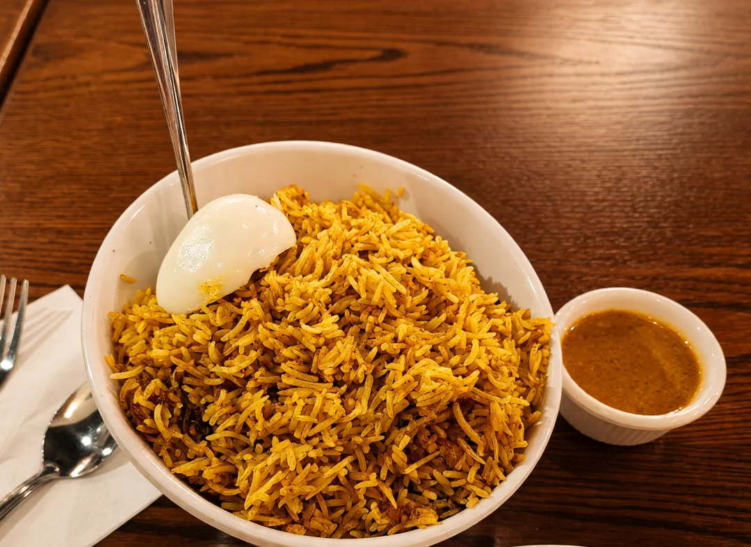 Hyderabadi chicken dum biryani with a boiled egg and a cup of salan at Bawarchi in Mississauga